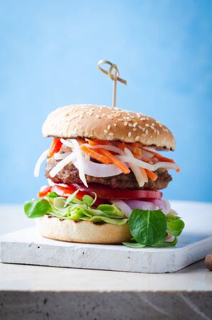 Burger with fermented foods kimchi, bbq beef cutlet on wooden over marble table.の写真素材