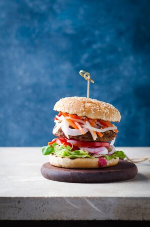 Burger with fermented foods kimchi, bbq beef cutlet on wooden over marble table.の写真素材