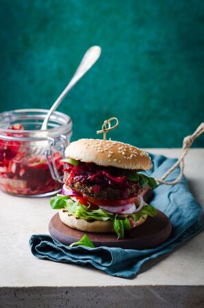 Burger with fermented cabbage,  beetroot dip, bbq beef cutlet on wooden over marble table.の写真素材