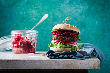 Burger with fermented cabbage,  beetroot dip, bbq beef cutlet on wooden over marble table.の写真素材