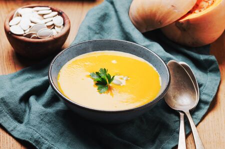 Pumpkin soup in blue bowl with pasrley and seeds.の写真素材