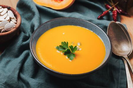 Pumpkin soup in blue bowl with pasrley and seeds.の写真素材