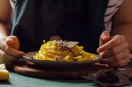 Female hands grating Parmesan cheese, black truffle onto pasta tagliatelle.の写真素材
