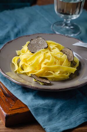 Italian cuisine- tagliatelle with black truffle on rustic plate.の写真素材