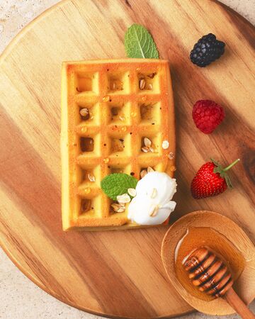 Belgian waffles with  summer fresh berries and honey on wooden board.Top view.の写真素材