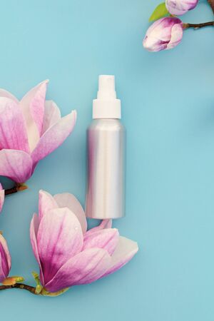 Beauty background for cosmetic products and magnolia blossom on pastel blue background. Spring skin care plan, top view, flat lay. Cosmetics and skin care concept.の写真素材