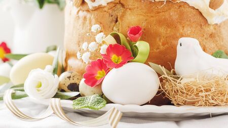 Italian Easter  cake with flowers eggs, dove on white plate. Selective focus, free text space.の写真素材