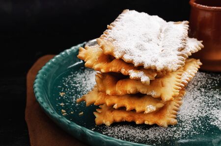 Typical Italian carnival fritters dusted with powdered sugar on   old black wooden table.の写真素材