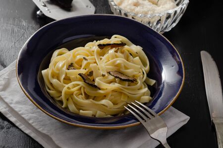 Tagliatelle al tartufo - Italian fresh  pasta with black truffle in  plate on  wooden rustic board.の写真素材