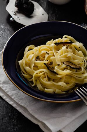 Tagliatelle al tartufo - Italian fresh  pasta with black truffle in  plate on  wooden rustic board.の写真素材