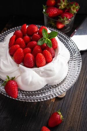 Strawberry Pavlova cake on glass plate  on black wooden table.の写真素材