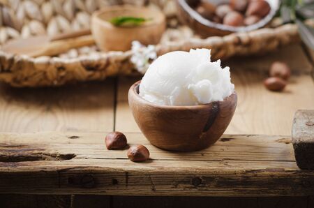 Shea butter in wooden bowl with nuts on old rustic table. Free text space.の写真素材