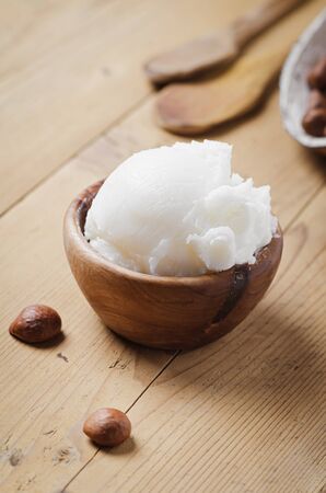 Shea butter in wooden bowl with nuts on old rustic table. Free text space.の写真素材