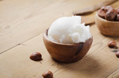 Shea butter in wooden bowl with nuts on old rustic table. Free text space.の写真素材