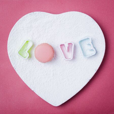 Creative layout made with Love letters on white plate and macaron. Greeting card. Colorful pink background.の写真素材