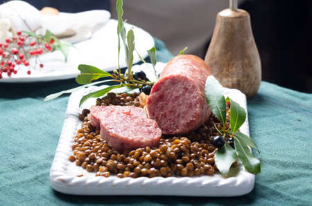 Italian large pork sausage cotechino served with lentils on white plate.の写真素材