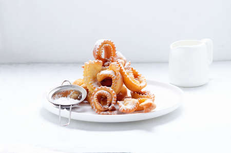 Italian carnival fritters galeno glove dusted with polwered sugar served on white plate.の写真素材