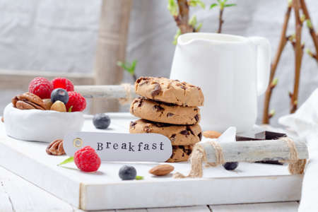Cookies with chocolate chips and fresh berries for breakfast on white wooden table.の写真素材