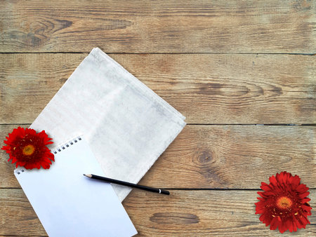 Red daisies and notepad on wooden board table. Top view with copy spase. Summer lifestyle or wedding concept.の写真素材