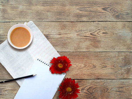 Mock up flatlay with red daisies, notepad and coffee on wooden background. Summer lifestyle or...