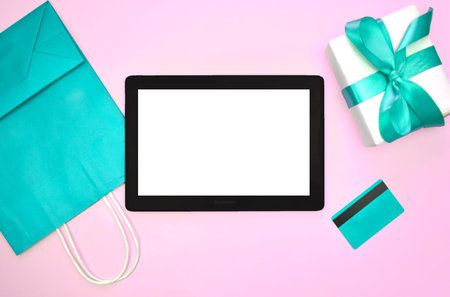 Mock up mInimalist flat lay with tablet, credit card, bag and gift box on pink background. Online...