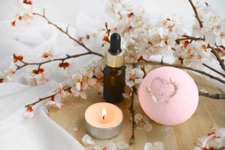 Aromatherapy concept with essential oil bottle, bath bomb, burning candle and blossoms branch. Spa...