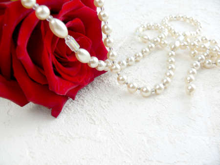 Red rose with pearls on white textured background. Elegant floral background for congratulations. Valentine s day, Mothers day or wedding greetind card. Selective focus with copyspace.の写真素材