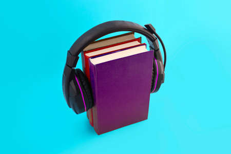 Audio book concept with headphones and stack of books on blue background. E-learning. Listening to a book.の写真素材