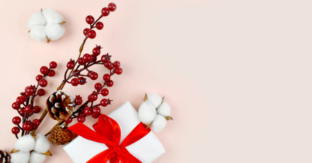 Happy Christmas composition with gift box, cotton flowers and red berries. Greeting minimalist...