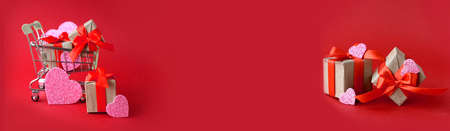 Greeting banner with trolley, gifts and decor hearts on red background. Minimalist trendy concept for Christmas, Valentines day, Mothers day, Women day or Black Friday sale.の写真素材