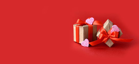 Greeting composition with gifts and decor hearts on red background. Minimalist concept for...