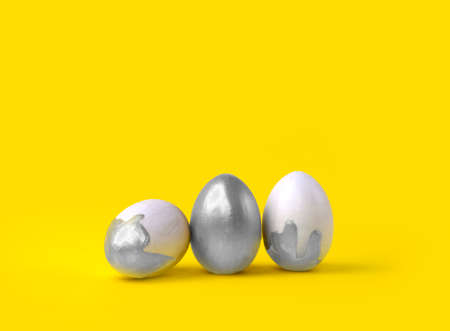 Minimalist Easter composition. Silver decorated eggs in row on yellow background. Trendy color concept. Happy Easter greeting card with copyspace.の写真素材