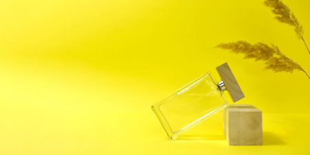 Glass perfume bottle, wooden podium and pampas grass on yellow background. Mock up luxury minimalist concept for branding, presentation. Trendy color design.の写真素材