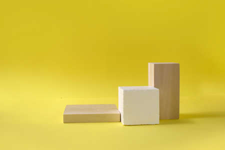 Mock up abstract minimal composition with geometric podiums for presentation. Trendy wood and stone pedestals, display blocks on yellow background. Advertising of spa, cosmetic, perfume productsの写真素材
