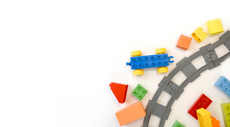 Colorful kids toys flat lay with toy train, railway, plastic and wooden blocks on white background....