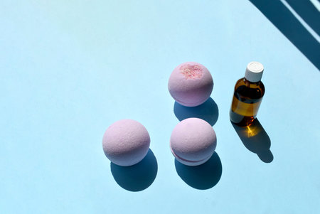 Spa cosmetics composition with essential oil bottle and bath bombs on blue background. Trendy...