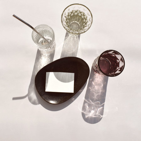 Luxury mockup still life table setting scene. Empty paper blank on stoneware plate, cocktail glass...