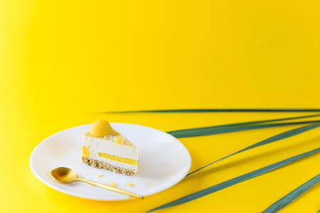 Slice of cashew cake with coconut and mango on a yellow background. Raw food dessert, vegetarian, vegan. Sugar free, gluten, lactose.の写真素材