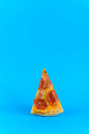 Slice of pepperoni pizza on a blue background.の写真素材