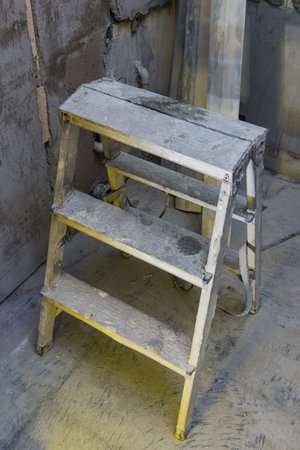 Repair in the apartment. Stepladder against the background of gray concrete walls.
