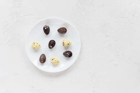 Chocolate eggs in a plate on a light table. Horizontal orientation, copy space, top view.の写真素材