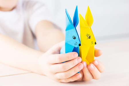 Paper rabbits in the hands of a kid on a light background.の写真素材