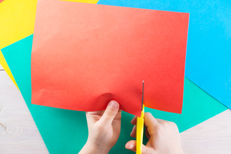 The kid cuts colored paper with scissors.の写真素材