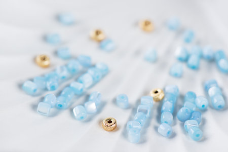 Jewelry making flatlay. Handmade jewelry, small business, hobby concept. Blue mother-of-pearl and gold beads on a tray, jewelry making.の写真素材