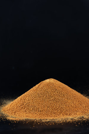 Saccharum officinarum, Panela or sugar cane candy. Heap of unrefined cane sugar Panela on black...