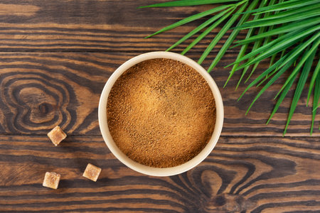 Unrefined cane sugar Panela in a bowl with palm branch on a wooden table. Saccharum officinarum, Panela or sugar cane candy. Top view.の写真素材