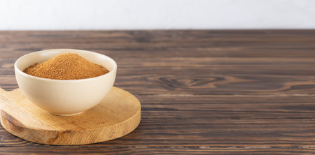 Unrefined cane brown sugar Panela in a bowl on a wooden table. Saccharum officinarum, Panela or sugar cane candy. Copy space.の写真素材