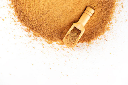 Pile with a wooden scoop with unrefined cane sugar Panela on a white background, top view, copy space. Saccharum officinarum, Panela or sugar cane candy.の写真素材