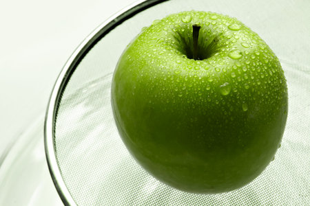 Wet green apple in brilliant drops of waterの写真素材