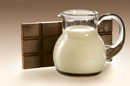 Jug with milk and slab chocolate under soft illumination の写真素材